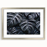 Framed botanical wall art design featuring a vibrant monstera plant illustration, set in a sleek silver frame with a white mat, perfect for modern decor.