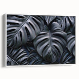 Framed botanical wall art featuring a Monstera plant design on canvas, showcasing vibrant green leaves against a white background, ideal for modern home decor.