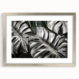 Botanical wall art featuring a Monstera design in a silver frame with a mat, showcasing vibrant green leaves against a soft background, ideal for home decor.