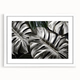 Framed botanical wall art featuring a Monstera plant design with vibrant green leaves, set against a white background, ideal for modern home decor.