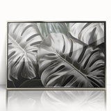 Framed wall art showcasing a vibrant botanical design featuring Monstera leaves, set in a sleek silver frame, perfect for modern home decor.
