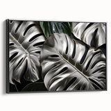 Framed wall art featuring a botanical monstera design on canvas, showcasing vibrant green leaves against a black background, ideal for modern home decor.