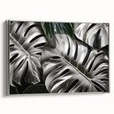 Framed wall art featuring a botanical monstera design, showcasing lush green leaves on a textured canvas with a sleek silver frame, ideal for modern decor.