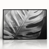 Framed wall art featuring a botanical monstera design in vibrant green and black, displayed in an acrylic frame, perfect for modern home decor.