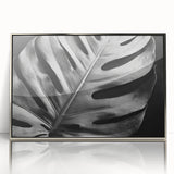 Framed wall art featuring a botanical monstera design, showcasing vibrant green leaves with a silver-acrylic frame, perfect for modern home decor.