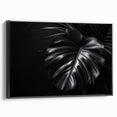 Framed canvas wall art featuring a botanical monstera design with vibrant green leaves on a black background, showcasing a modern aesthetic for home decor.