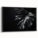 Framed canvas wall art featuring a botanical monstera design with vibrant green leaves on a black background, showcasing a modern aesthetic for home decor.