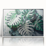 Framed wall art showcasing a vibrant botanical monstera design with lush green leaves against a white background, perfect for home decor and nature enthusiasts.