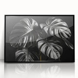 Framed wall art featuring a botanical monstera design in vibrant green tones, displayed against a sleek black frame, perfect for modern home decor and plant enthusiasts.