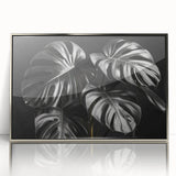 Framed botanical wall art featuring a Monstera plant design with a sleek silver frame, showcasing vibrant green leaves ideal for home decor or office aesthetics.