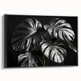 Framed botanical wall art featuring a Monstera leaf design on a black background, showcasing vibrant green hues and elegant framing, ideal for modern decor.