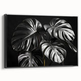 Framed botanical wall art featuring a Monstera leaf design on a black background, showcasing vibrant green hues and elegant framing, ideal for modern decor.