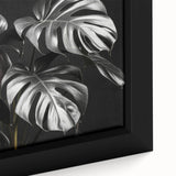 Close-up of a framed canvas showcasing vibrant monstera leaves in a botanical design, perfect for adding a tropical touch to any wall decor.