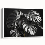 Framed canvas wall art showcasing a botanical monstera design with vibrant green leaves against a white background, perfect for modern home decor.