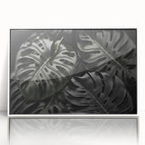 Framed wall art showcasing a botanical monstera design in vibrant green hues, set against a sleek white background, ideal for modern home decor.