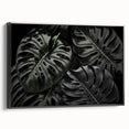Framed canvas wall art featuring a botanical monstera design in vibrant green and black tones, showcasing tropical leaves against a minimalist background, perfect for modern decor.