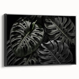 Framed canvas wall art featuring a botanical monstera design in vibrant green and black tones, showcasing tropical leaves against a minimalist background, perfect for modern decor.