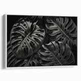 Framed canvas wall art featuring a botanical monstera leaf design against a white background, showcasing vibrant green hues and intricate details, perfect for home decor.