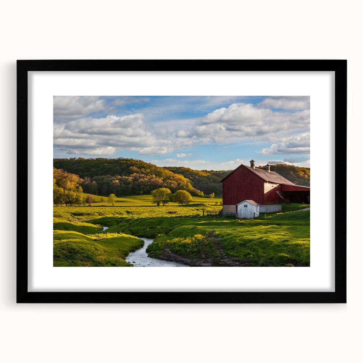 Framed wall art featuring a serene landscape of rustic barns, set in a black frame with a mat, ideal for enhancing home decor with a touch of rural charm.