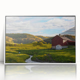 Framed acrylic wall art showcasing a serene landscape with a rustic barn, set against a vibrant sunset. The artwork features warm colors and intricate details, perfect for home decor enthusiasts.