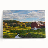 Stretched canvas wall art showcasing a serene landscape with a rustic barn, leaning against a neutral wall, perfect for farmhouse decor enthusiasts. Ideal for adding warmth to living spaces.