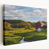 Stretched canvas wall art depicting a scenic landscape with a rustic red barn surrounded by lush greenery and a clear blue sky, perfect for home decor.