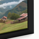 Close-up view of a framed canvas wall art showcasing a serene landscape with rustic barns, rich green fields, and a vibrant blue sky, perfect for home decor.