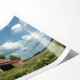 Rustic landscape barn wall art print showcasing a serene countryside scene with vibrant green fields and a blue sky, perfect for home decor or as a gift.