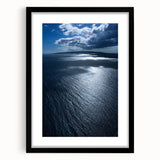 Framed wall art showcasing a vibrant beach landscape design, featuring soft blues and warm sandy tones, elegantly matted and presented in a sleek black frame.