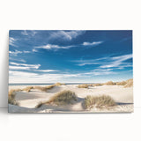 Stretched canvas wall art showcasing a vibrant beach landscape with soft waves and golden sands, leaning against a neutral wall, perfect for coastal-themed decor.