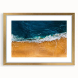 Framed wall art featuring a serene beach landscape with a gold mat, ideal for home decor. The piece showcases calming ocean colors, enhancing any room's ambiance.