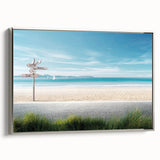 Framed canvas wall art featuring a serene beach landscape with vibrant blues and sandy tones, elegantly displayed with a silver frame, perfect for home decor.