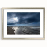 Framed wall art showcasing a serene beach landscape with soft waves and a colorful sunset, elegantly presented in a silver frame with a mat, perfect for home decor.