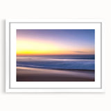 Framed wall art depicting a serene beach landscape with soft waves and a blue sky, featuring a white mat and sleek frame, perfect for coastal decor. Ideal for enhancing living spaces.