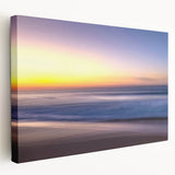Stretched canvas artwork depicting a serene beach landscape with soft pastel colors, showcasing gentle waves and a tranquil sky, ideal for home decor.