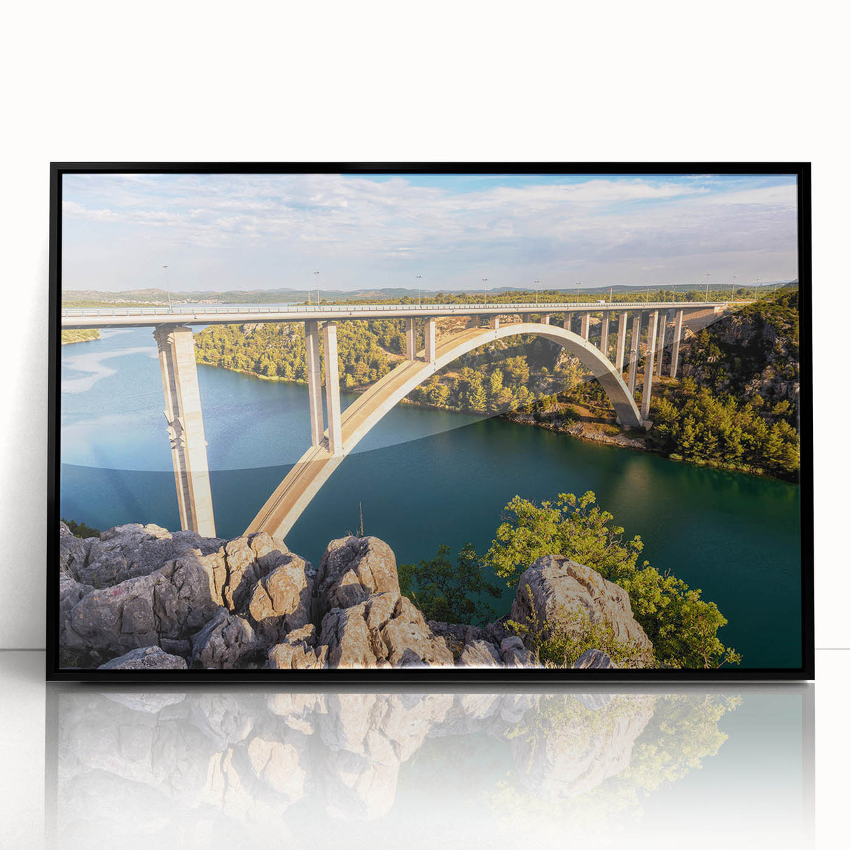 Framed acrylic wall art showcasing a modern landscape design with a bridge, featuring a sleek black frame and vibrant colors, ideal for contemporary home decor.