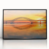 Framed acrylic wall art of a serene landscape featuring a bridge over a tranquil river, with vibrant colors and a sleek black frame, ideal for modern decor.
