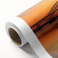 Rolled canvas showcasing a vibrant landscape with a bridge, ideal for home decor, elegantly packaged in a protective cardboard tube for easy transport.