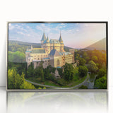 Framed wall art featuring a serene landscape with a majestic castle, set against a vibrant sunset. The acrylic surface enhances color depth, perfect for home decor.