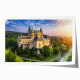 Rolled print of a picturesque landscape featuring a medieval castle surrounded by lush greenery, showcasing vibrant colors and intricate details, ideal for home decor.
