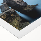 Vibrant rolled canvas wall art depicting dramatic seaside cliffs at sunset, showcasing rich colors of orange and blue, perfect for enhancing modern home decor.