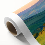 Rolled canvas wall art showcasing a serene countryside landscape with lush green fields and a vibrant sunset, elegantly packaged in a protective cardboard tube for easy display.