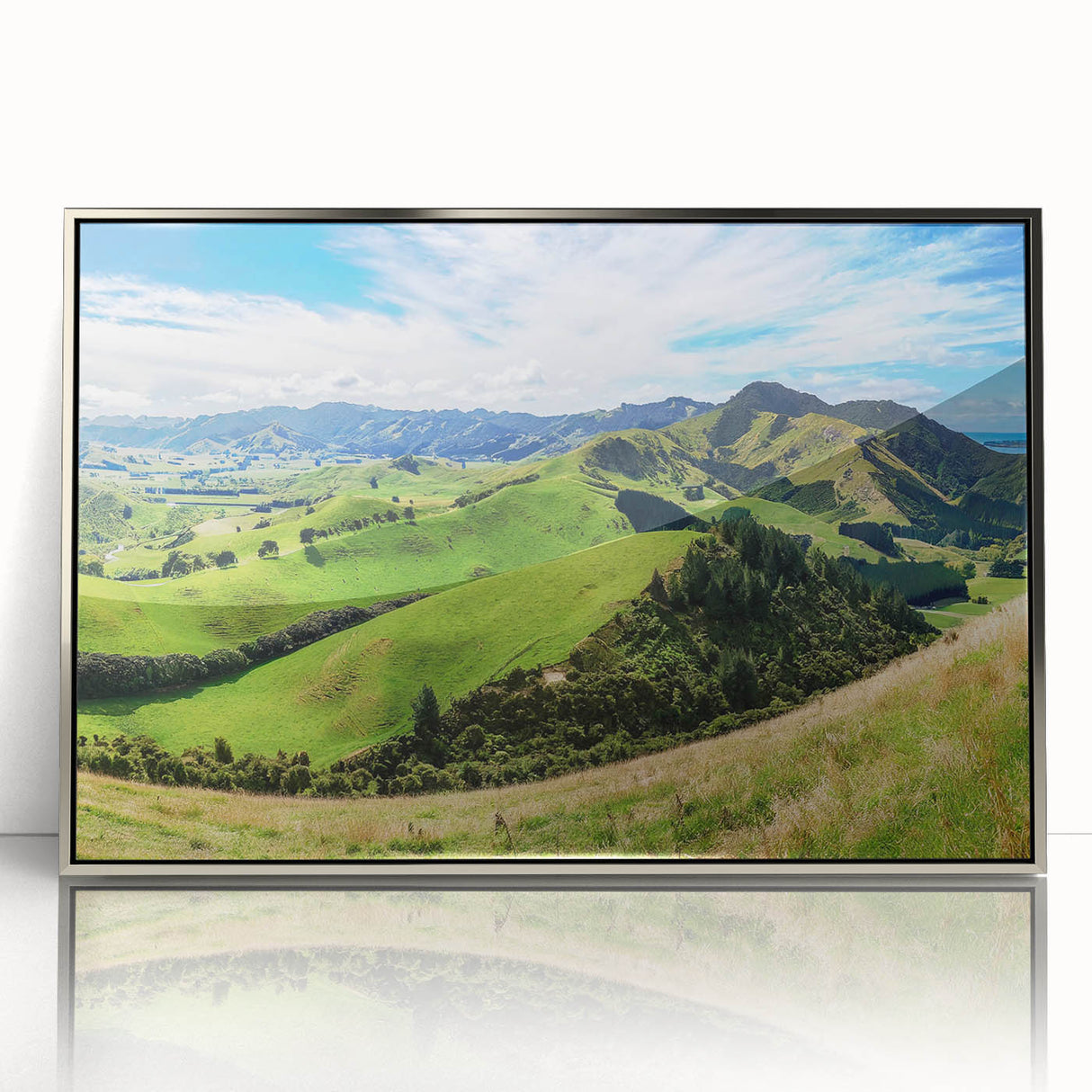 Framed acrylic wall art showcasing a serene countryside landscape design, featuring vibrant greens and soft blues, elegantly displayed with a silver frame.