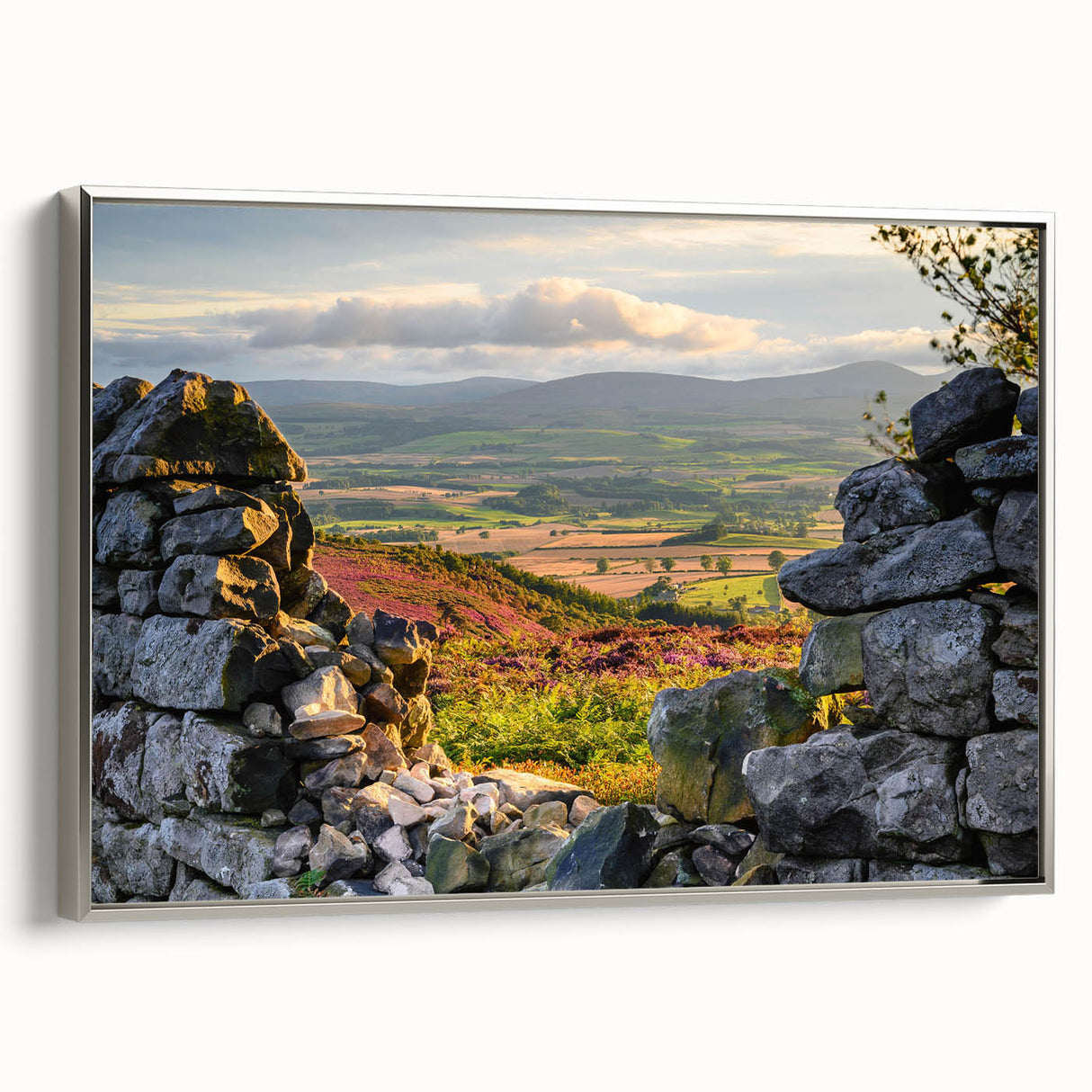 Framed canvas wall art showcasing a serene countryside landscape, featuring lush green fields and a tranquil sky, elegantly displayed with a silver frame.