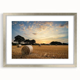 Framed wall art depicting a serene countryside landscape, featuring lush green fields and a clear blue sky, with a silver mat and frame for an elegant finish.