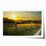 Vibrant countryside landscape wall art print showcasing rolling green hills, a clear blue sky, and soft white clouds, rolled and ready for display or framing.