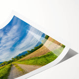 Rolled landscape wall art print showcasing a serene countryside scene with vibrant green fields and a clear blue sky, elegantly packaged for display.