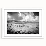 Framed wall art featuring a serene countryside landscape with lush greenery and rolling hills, set in a sleek white frame, ideal for home decor.