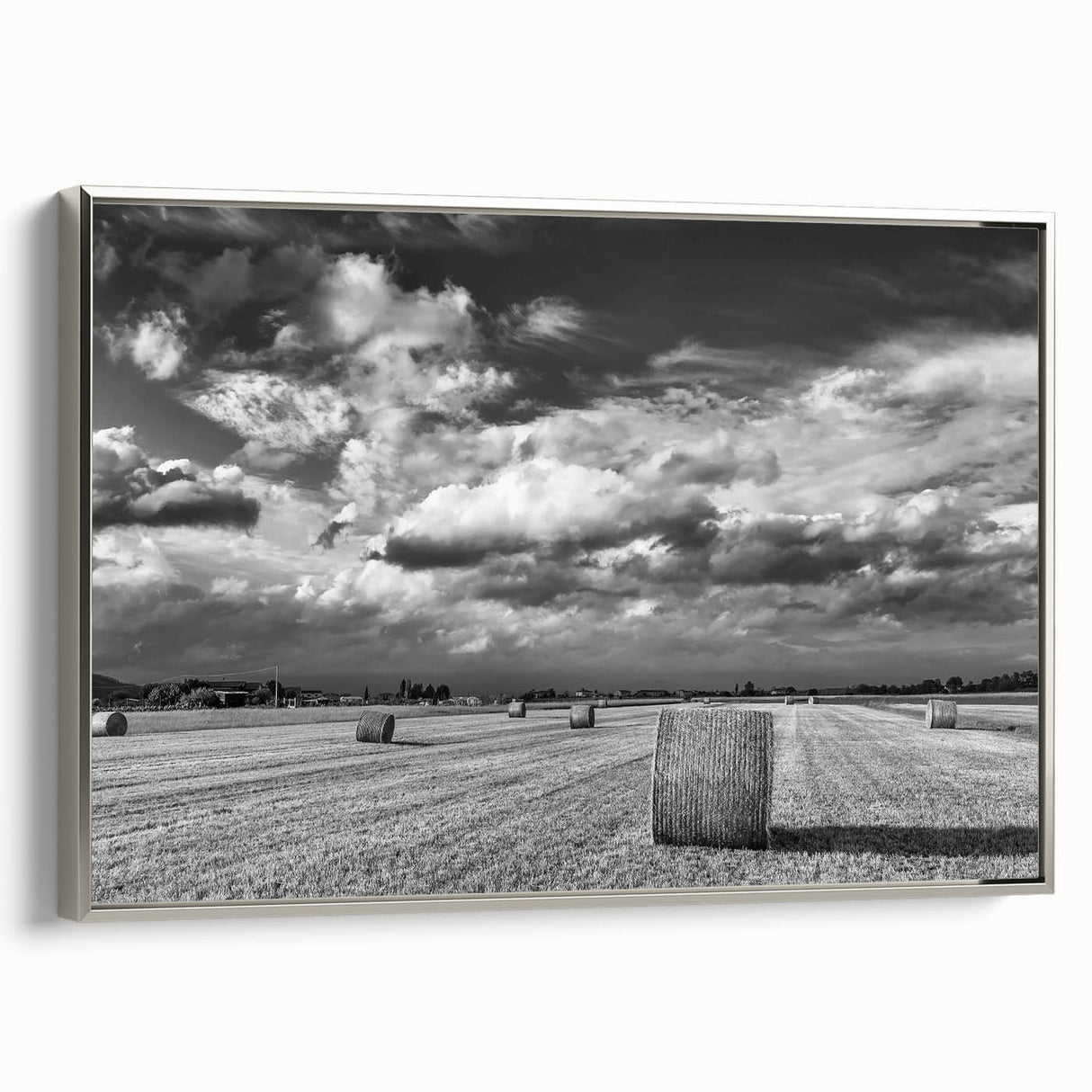 Framed canvas wall art showcasing a serene countryside landscape with vibrant green fields and a cloudy sky, elegantly displayed with silver accents.