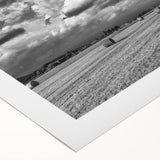Rolled canvas artwork showcasing a serene countryside landscape with vibrant green fields, soft blue skies, and rustic farmhouses, perfect for home decor.